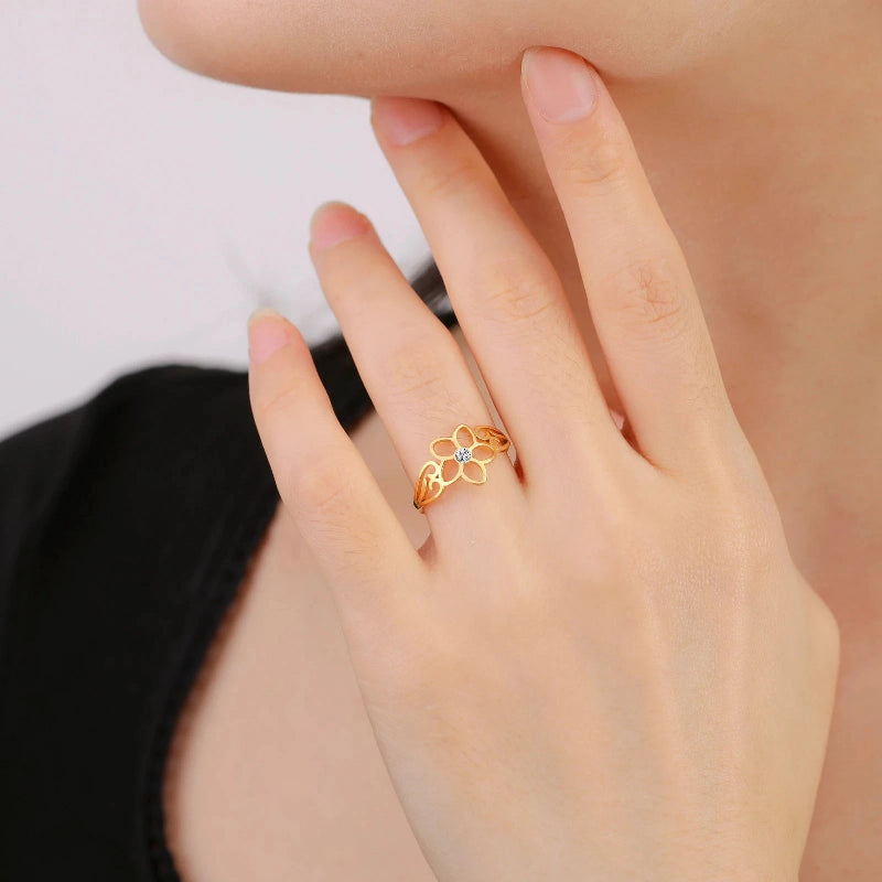 Sormus, jossa on viiden terälehden kukka ja kultainen zirkoni