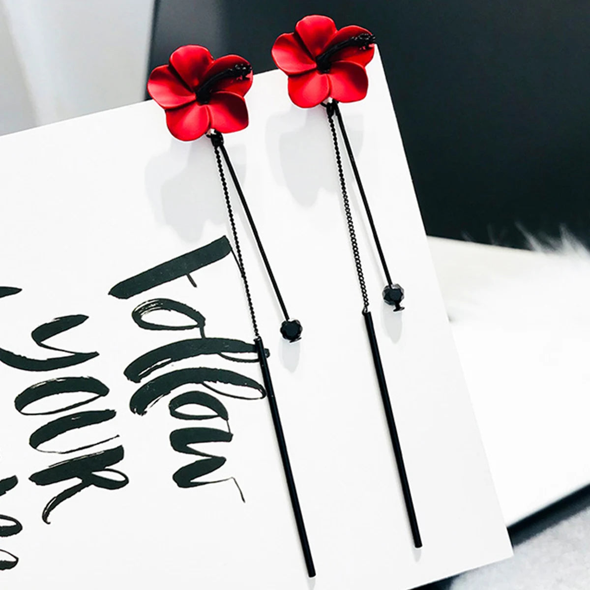 Punainen kukka ja punainen ketju roikkuvat korvakorut