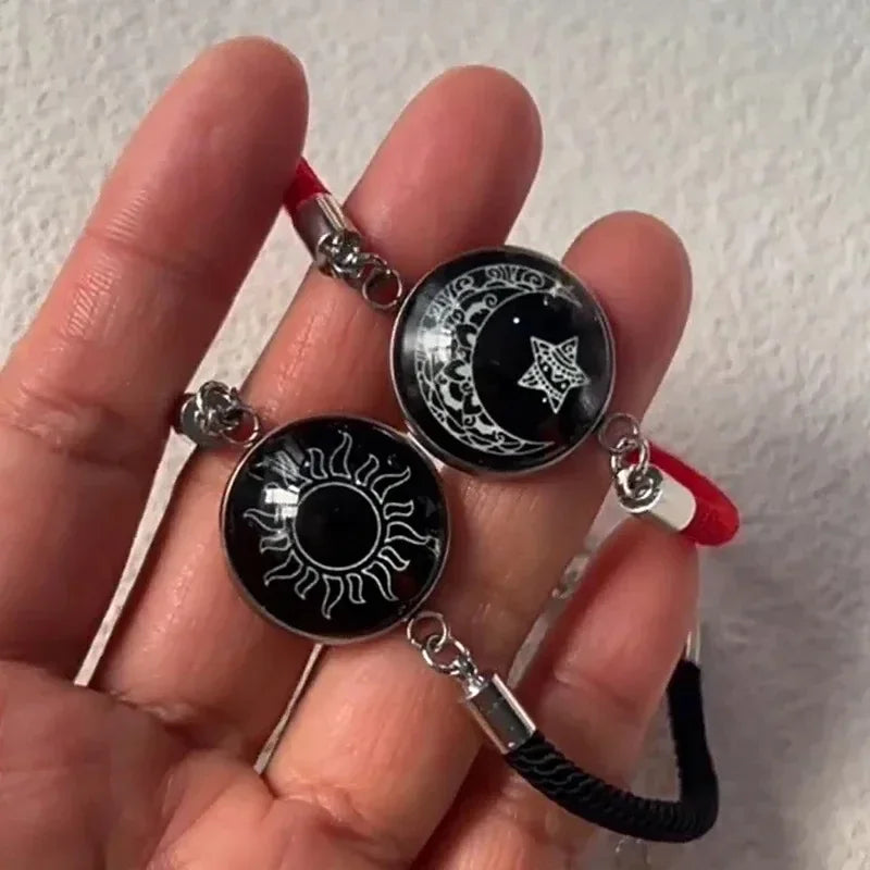 Rannekoru punaisella ja mustalla hehkuvalla puolikuulla ja auringolla