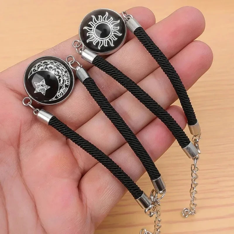 Rannekoru mustalla hehkuvalla puolikuulla ja auringolla