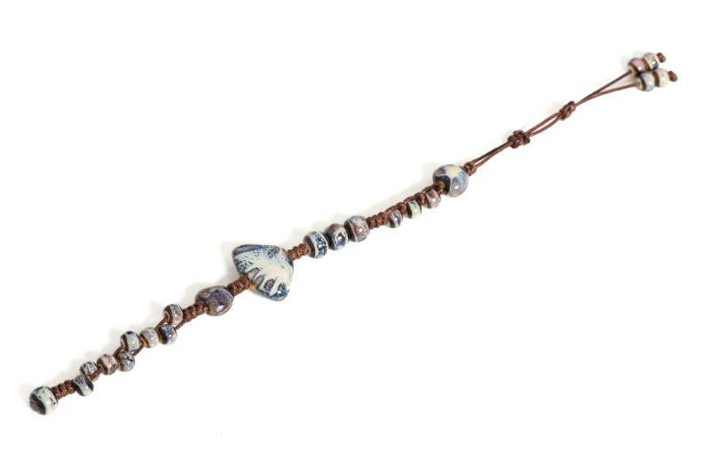 Sininen punottu rannekoru, jossa simpukka