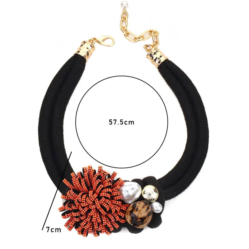 Kaulakoru, jossa on punainen kukka-riipus ja helmiä