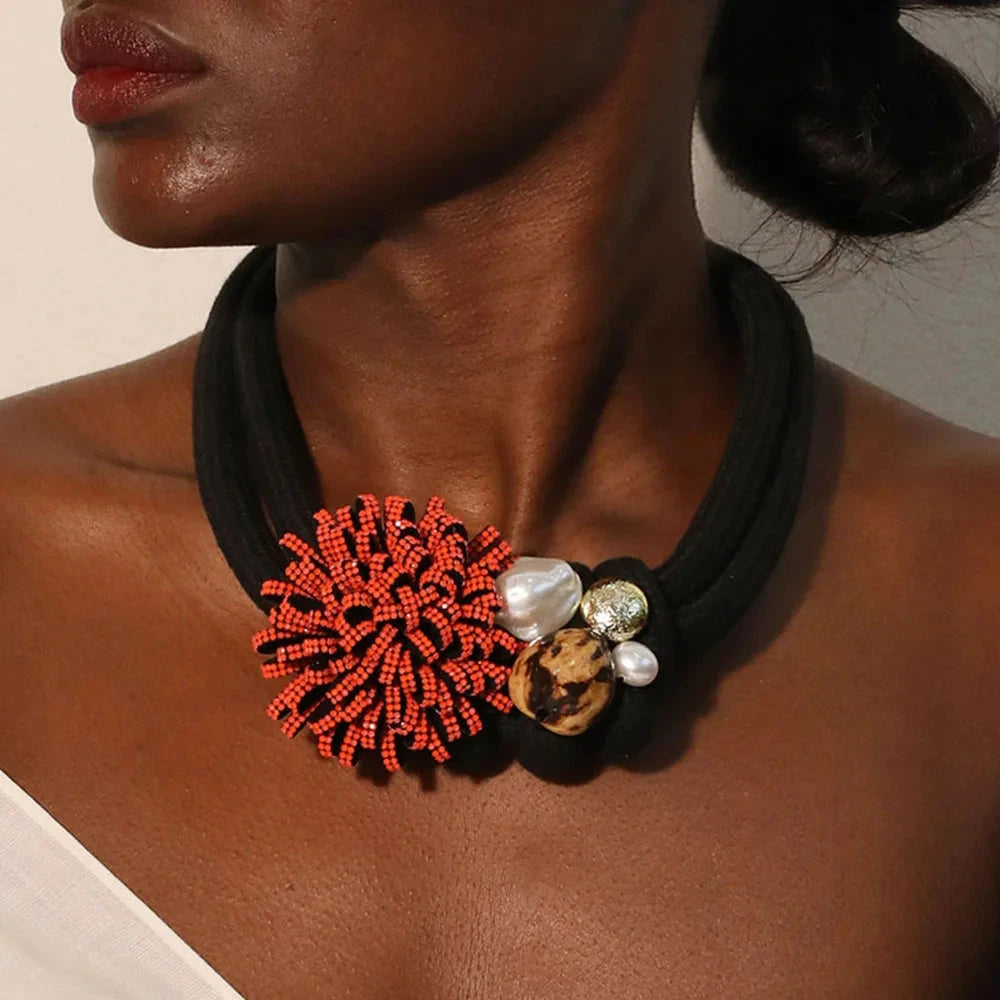 Kaulakoru, jossa on punainen kukka-riipus ja helmiä