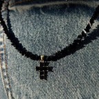 Kaulakoru, jossa musta kimalteleva risti choker-riipuksena