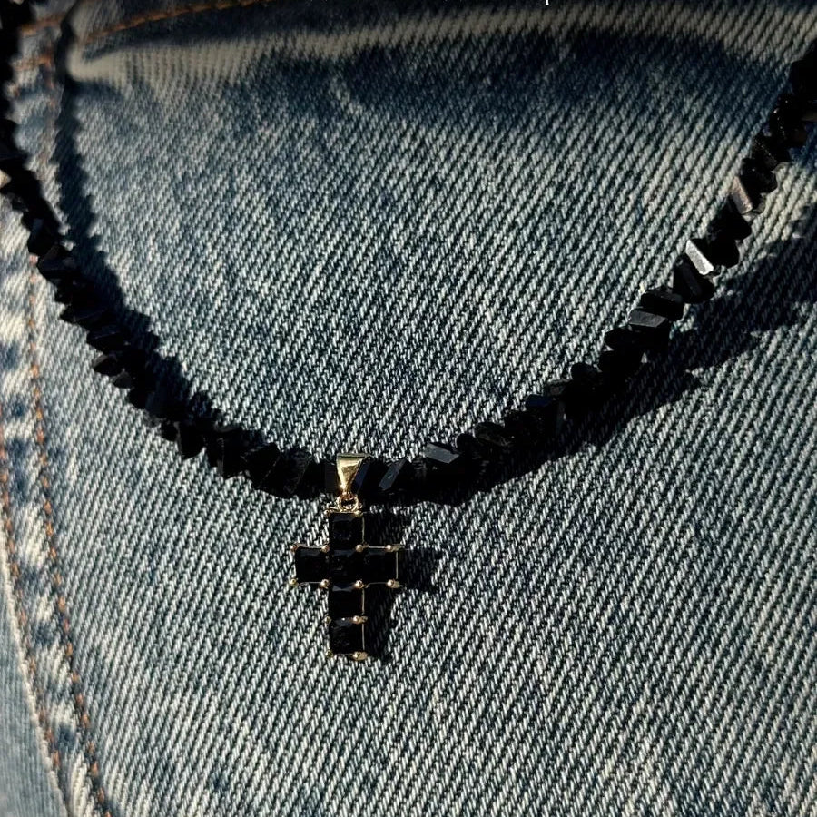 Kaulakoru, jossa musta kimalteleva risti choker-riipuksena