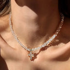 Kaulakoru, jossa valkoinen kimalteleva risti choker-riipuksena