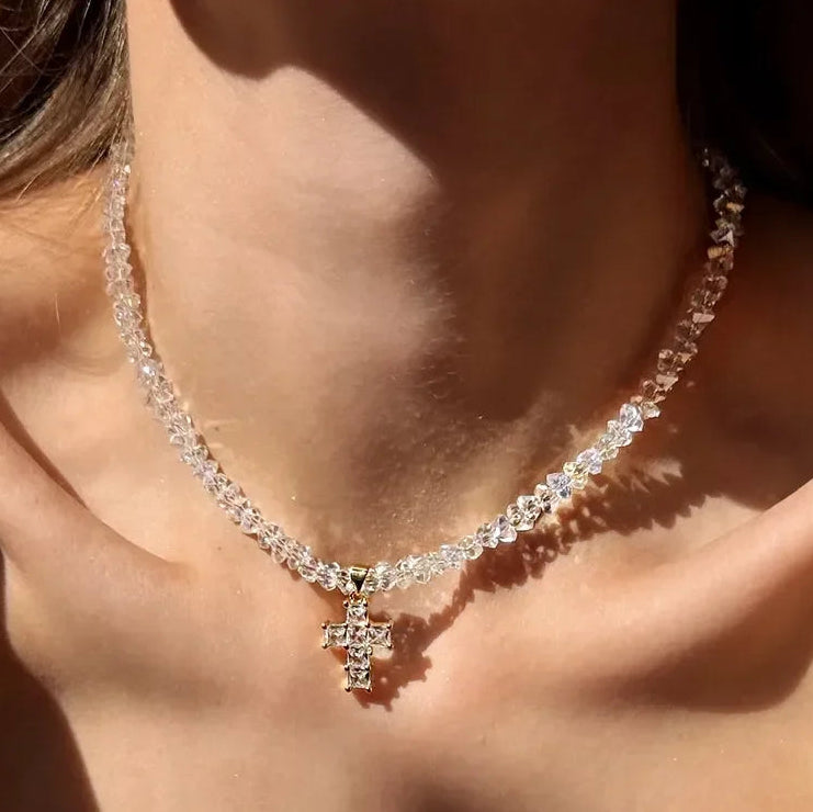 Kaulakoru, jossa valkoinen kimalteleva risti choker-riipuksena