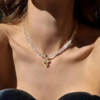 Kaulakoru, jossa valkoinen kimalteleva risti choker-riipuksena