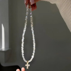 Kaulakoru, jossa valkoinen kimalteleva risti choker-riipuksena