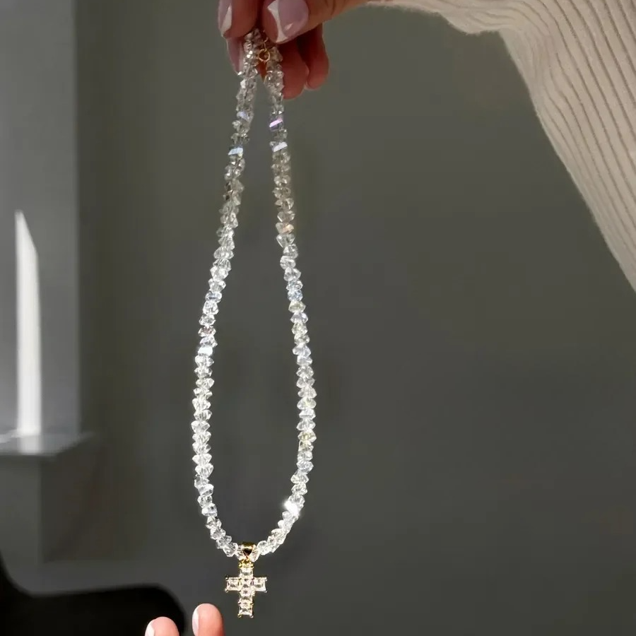 Kaulakoru, jossa valkoinen kimalteleva risti choker-riipuksena