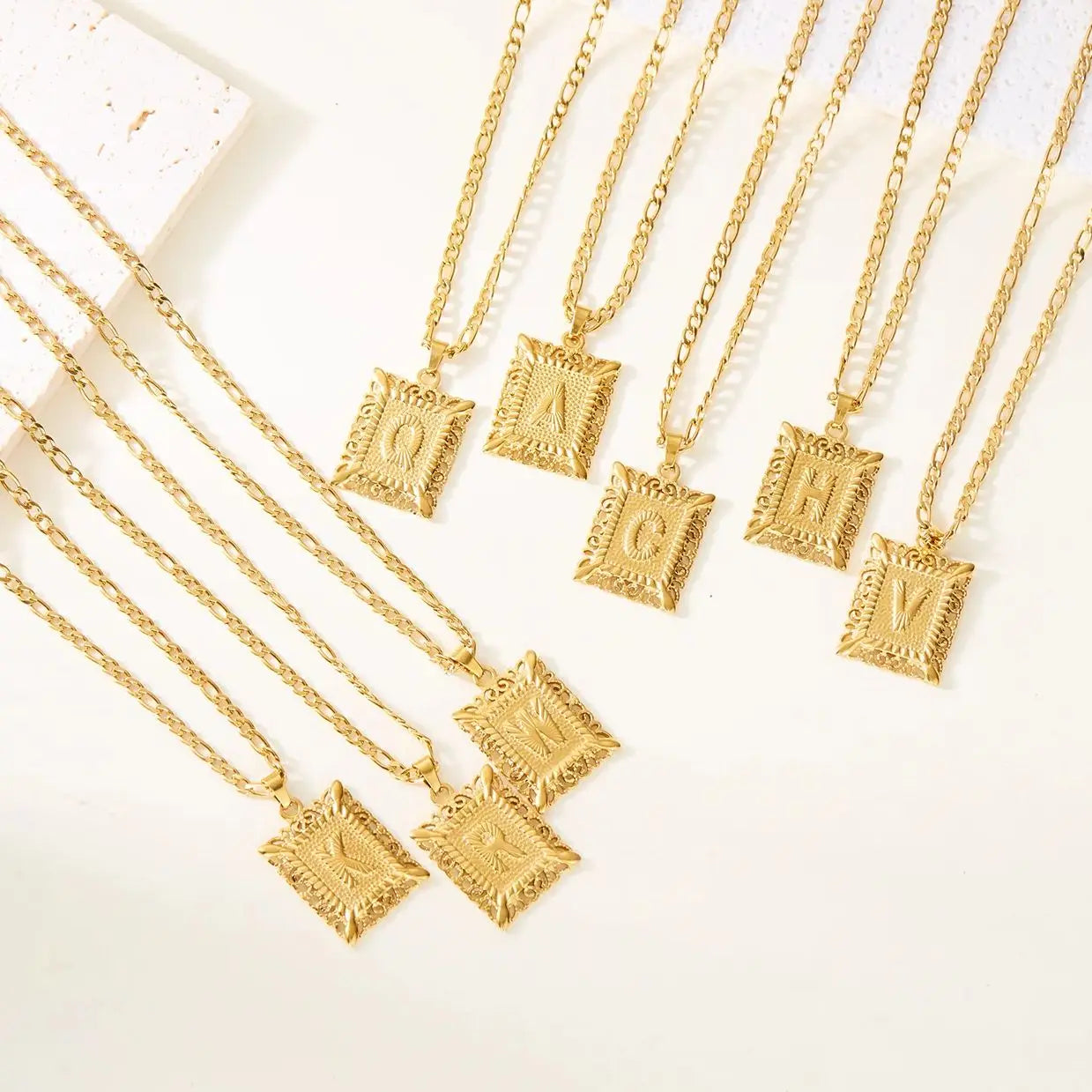 Kaulakoru, jossa on suorakulmainen riipus ja kirjain