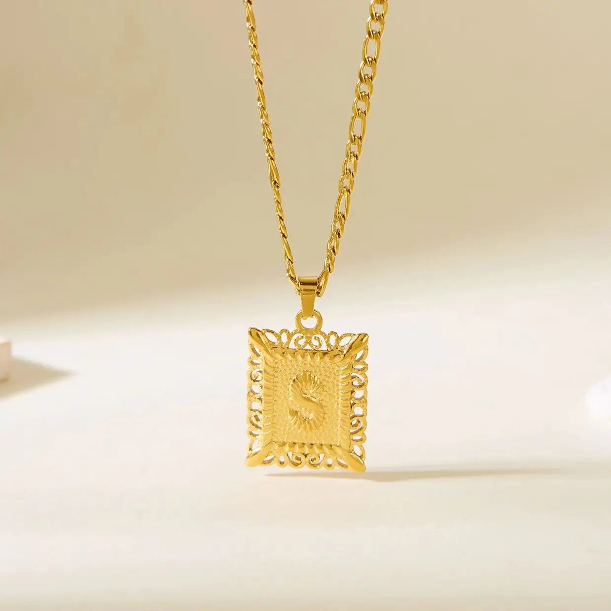 Kaulakoru, jossa on suorakulmainen riipus ja kirjain s