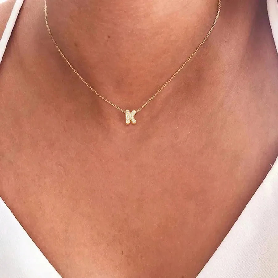 Naisen choker-kaulakoru minimalistisella k-kirjaimen riipuksella